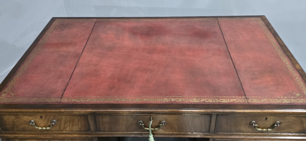 A double-pedestal mahogany partners desk featuring a leather-inset writing surface and brass swan-neck handles on multiple drawers. View III
