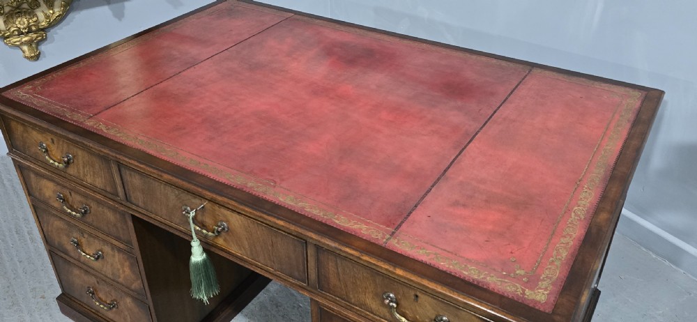 A double-pedestal mahogany partners desk featuring a leather-inset writing surface and brass swan-neck handles on multiple drawers. View V