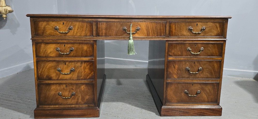 A double-pedestal mahogany partners desk featuring a leather-inset writing surface and brass swan-neck handles on multiple drawers. View VI
