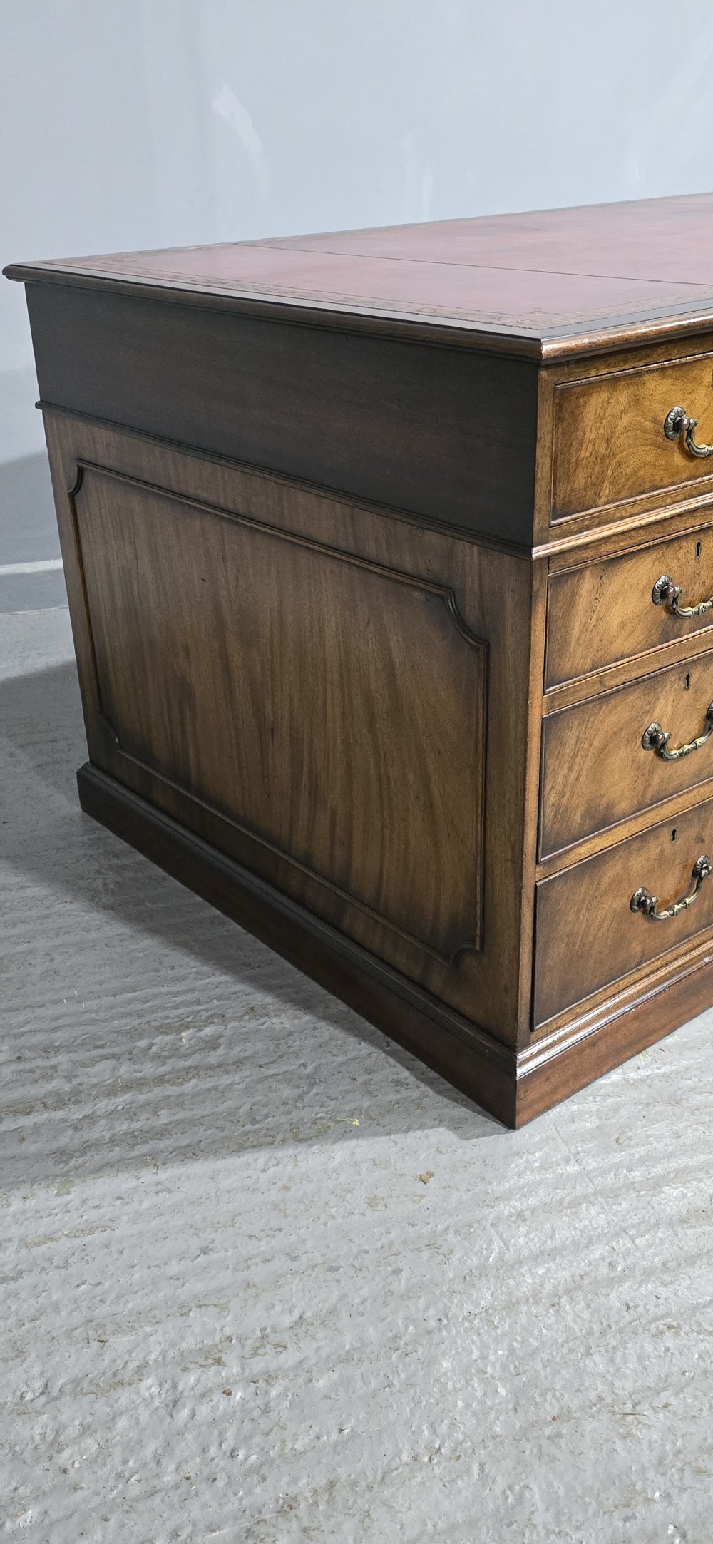A double-pedestal mahogany partners desk featuring a leather-inset writing surface and brass swan-neck handles on multiple drawers. View VII