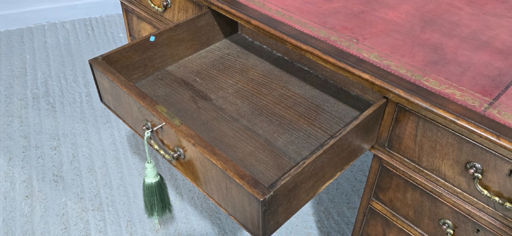 A double-pedestal mahogany partners desk featuring a leather-inset writing surface and brass swan-neck handles on multiple drawers. View IX