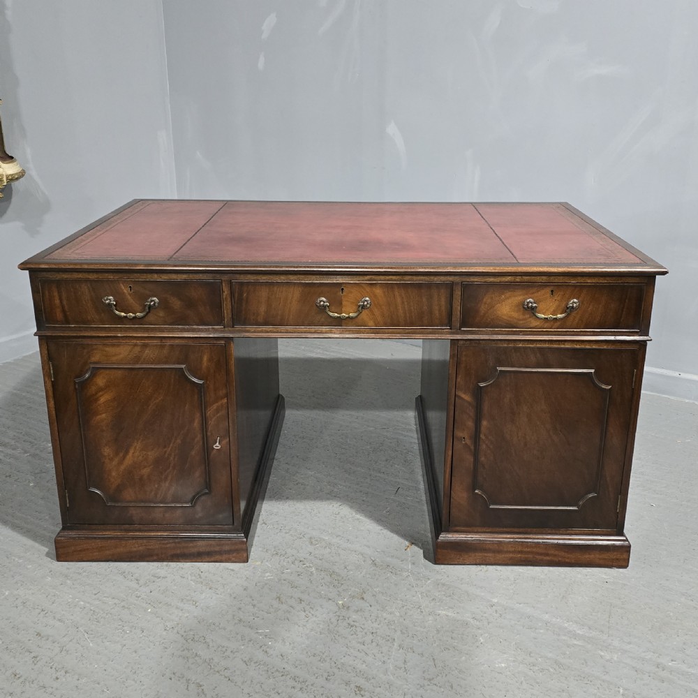 A double-pedestal mahogany partners desk featuring a leather-inset writing surface and brass swan-neck handles on multiple drawers. View XI