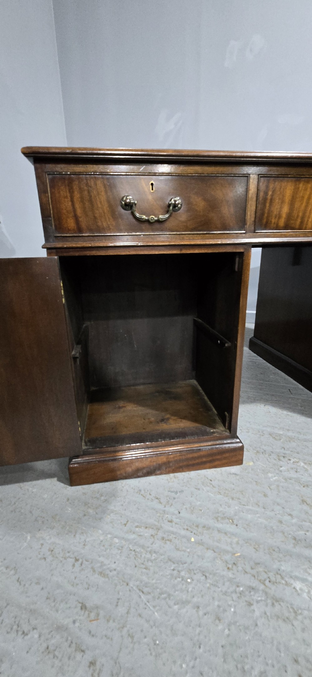 A double-pedestal mahogany partners desk featuring a leather-inset writing surface and brass swan-neck handles on multiple drawers. View XIV