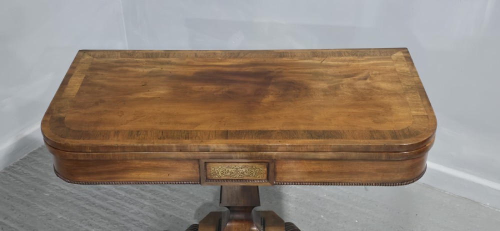 A Regency brass inlaid wooden card table featuring a fold-over top, central pedestal column, and four splayed legs with brass paw feet. View II