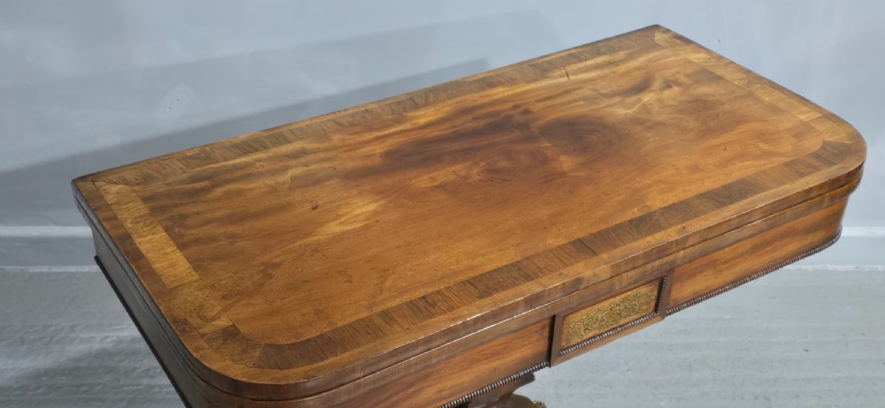 A Regency brass inlaid wooden card table featuring a fold-over top, central pedestal column, and four splayed legs with brass paw feet. View III