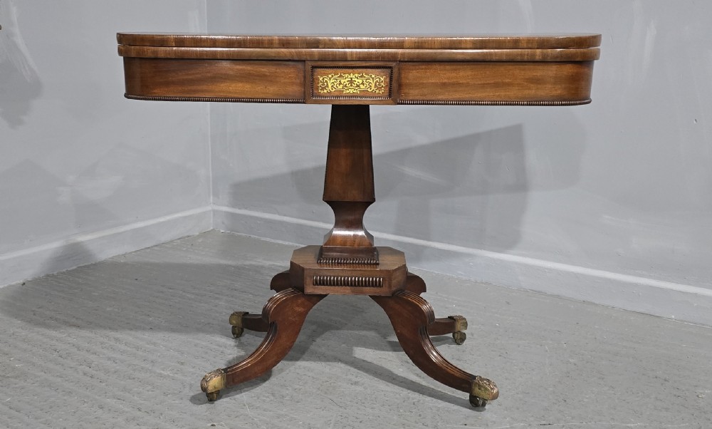 A Regency brass inlaid wooden card table featuring a fold-over top, central pedestal column, and four splayed legs with brass paw feet. View VI