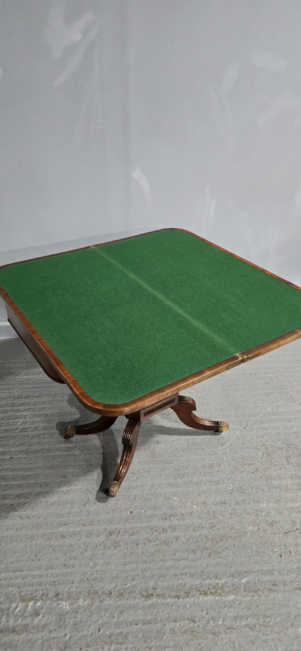 A Regency brass inlaid wooden card table featuring a fold-over top, central pedestal column, and four splayed legs with brass paw feet. View XVI