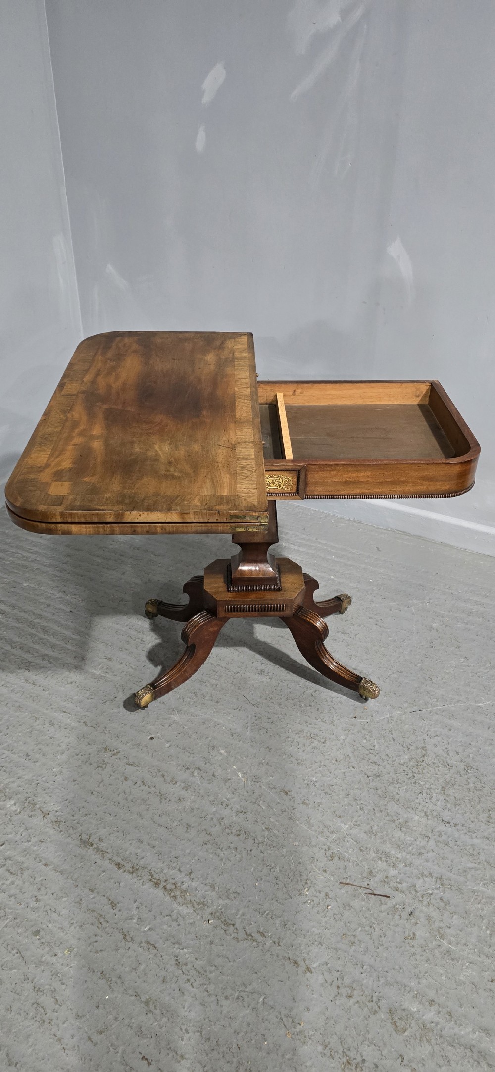A Regency brass inlaid wooden card table featuring a fold-over top, central pedestal column, and four splayed legs with brass paw feet. View XVIII
