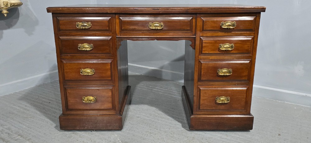 A warm brown mahogany pedestal desk featuring a green leather writing top, nine drawers, and brass swan-neck handles set upon twin plinth bases. View II