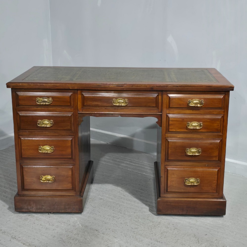 A warm brown mahogany pedestal desk featuring a green leather writing top, nine drawers, and brass swan-neck handles set upon twin plinth bases.