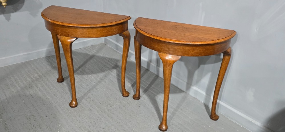 A pair of semi-circular oak console tables with smooth tops and slender cabriole legs terminating in pad feet. View IX