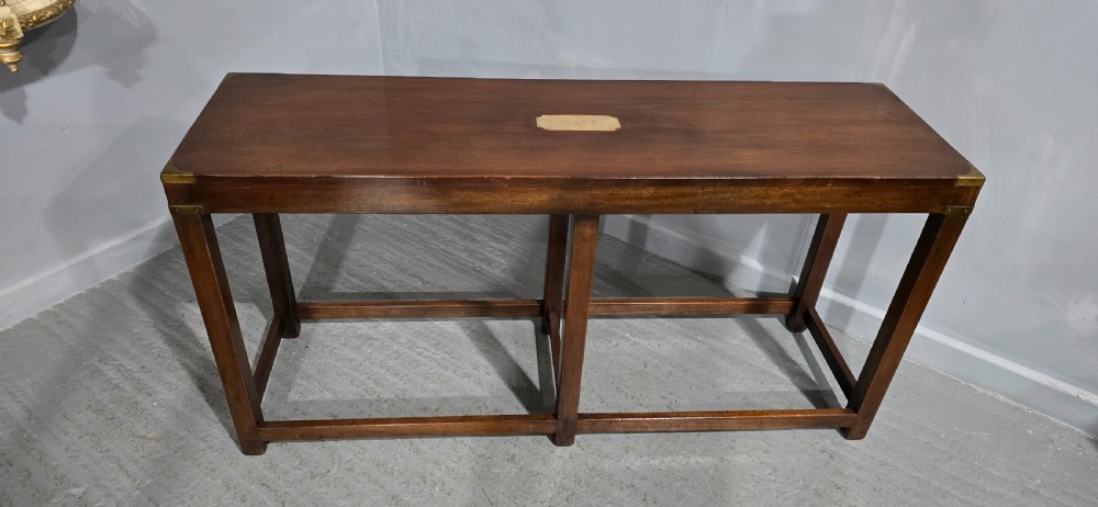 A rectangular mahogany campaign console table featuring brass corner mounts, an inset central brass plaque, and straight squared legs connected by a full box stretcher. View VIII