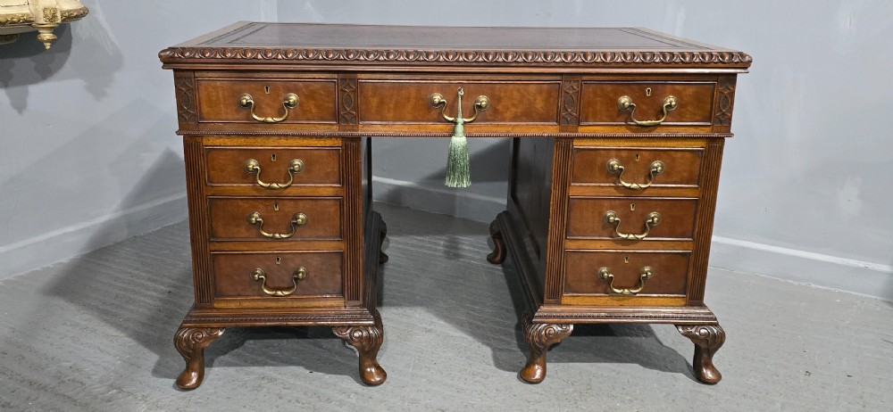 A Chippendale style mahogany pedestal desk featuring nine drawers with brass handles, a brown leather writing surface, and carved cabriole legs with ball-and-claw feet. View II