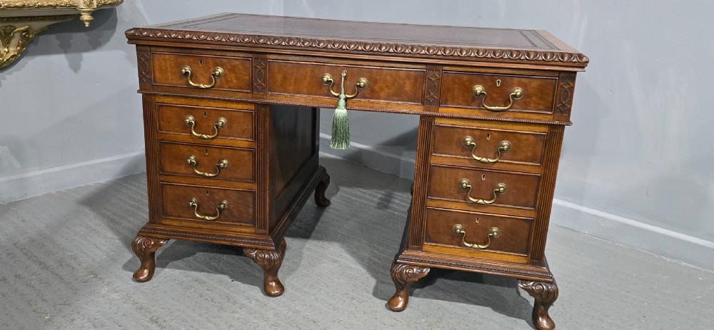 A Chippendale style mahogany pedestal desk featuring nine drawers with brass handles, a brown leather writing surface, and carved cabriole legs with ball-and-claw feet. View IV
