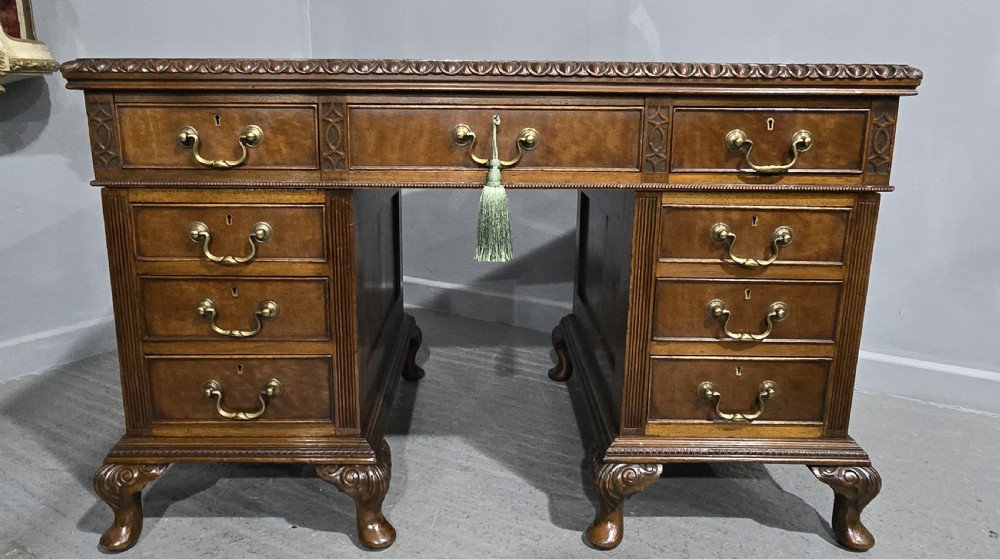 A Chippendale style mahogany pedestal desk featuring nine drawers with brass handles, a brown leather writing surface, and carved cabriole legs with ball-and-claw feet. View VI