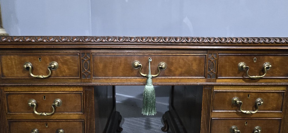 A Chippendale style mahogany pedestal desk featuring nine drawers with brass handles, a brown leather writing surface, and carved cabriole legs with ball-and-claw feet. View VII