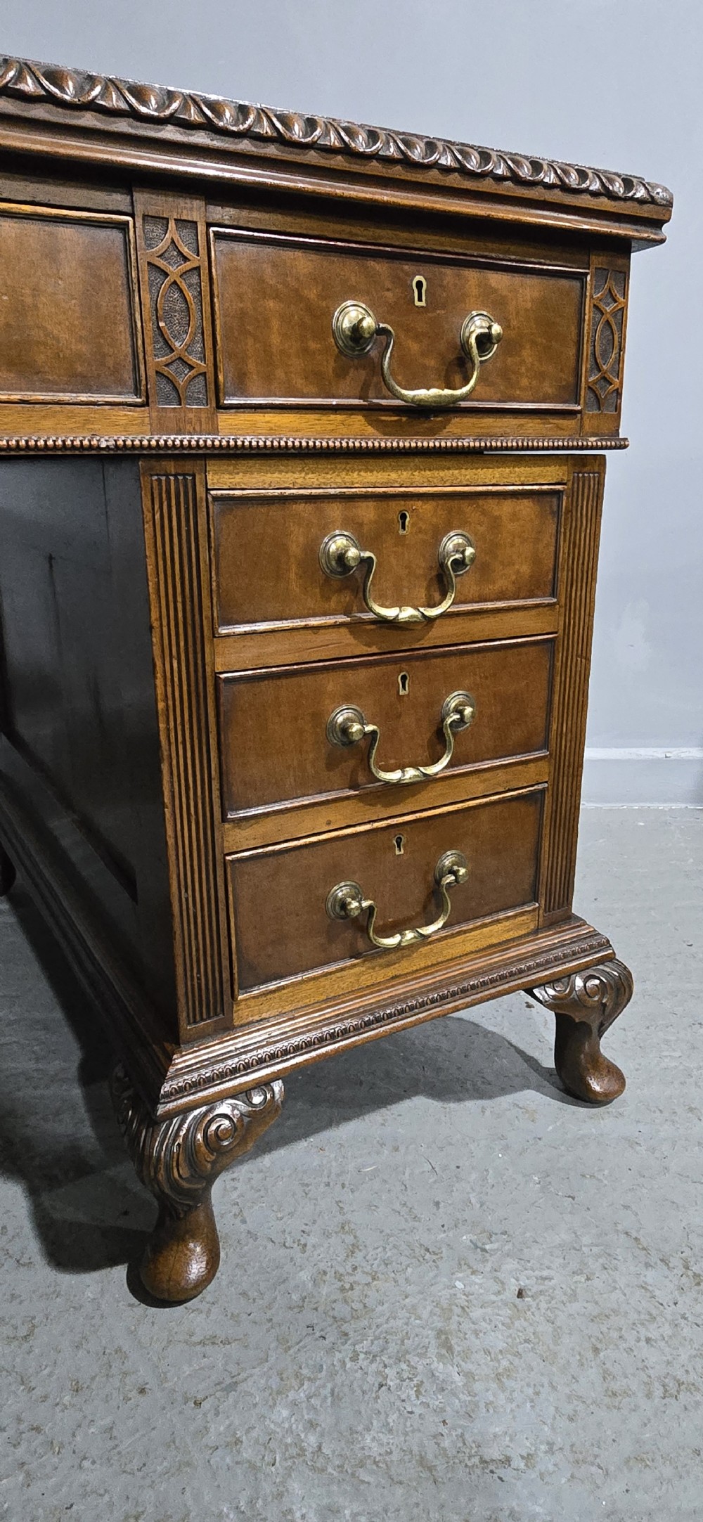 A Chippendale style mahogany pedestal desk featuring nine drawers with brass handles, a brown leather writing surface, and carved cabriole legs with ball-and-claw feet. View X