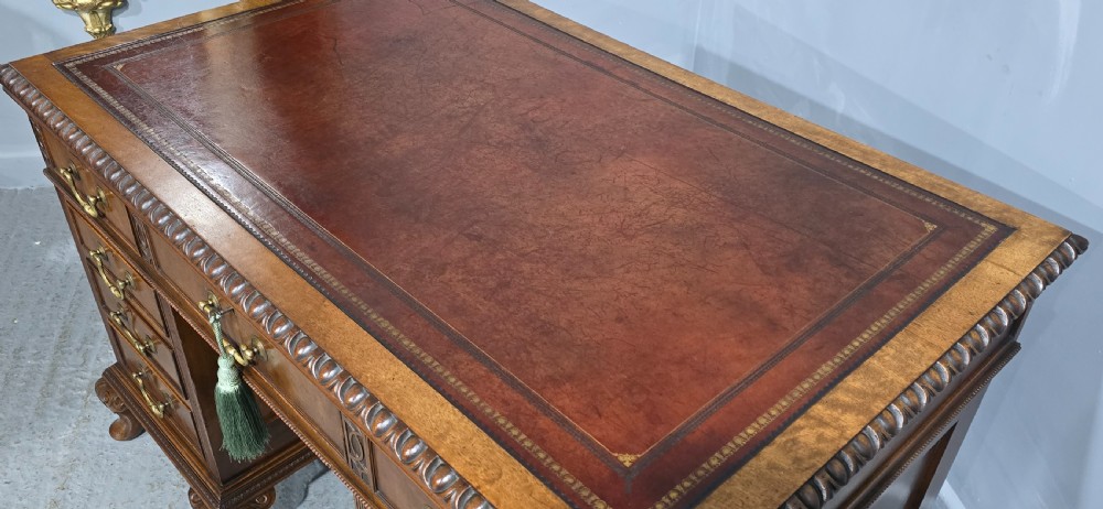 A Chippendale style mahogany pedestal desk featuring nine drawers with brass handles, a brown leather writing surface, and carved cabriole legs with ball-and-claw feet. View XVI