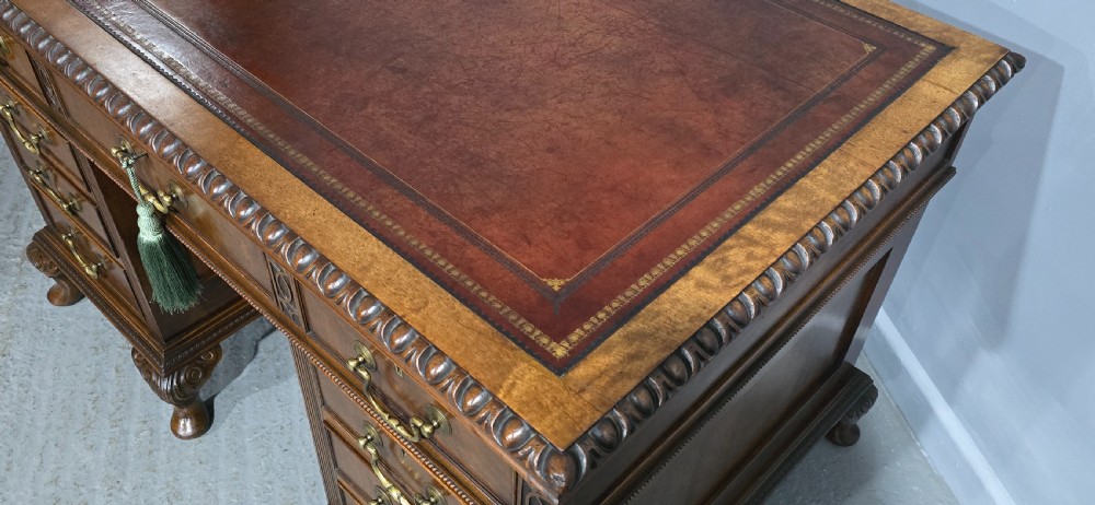 A Chippendale style mahogany pedestal desk featuring nine drawers with brass handles, a brown leather writing surface, and carved cabriole legs with ball-and-claw feet. View XVIII