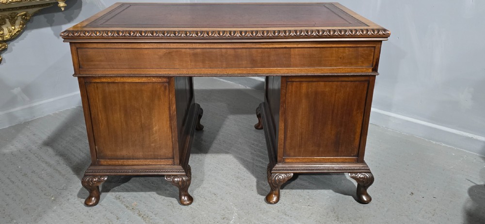 A Chippendale style mahogany pedestal desk featuring nine drawers with brass handles, a brown leather writing surface, and carved cabriole legs with ball-and-claw feet. View XX