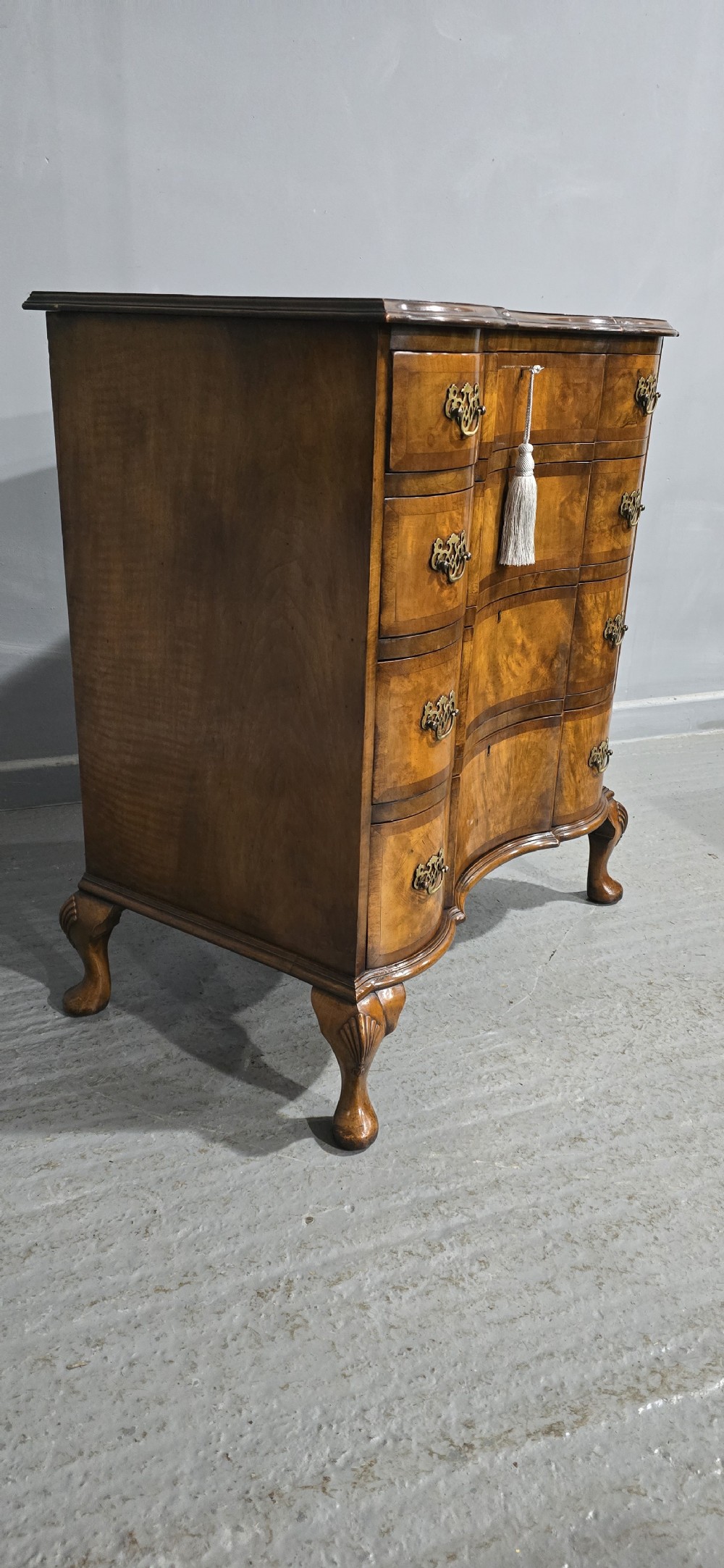 A four-drawer walnut chest of drawers featuring an inward-curving concave front, brass handles, and cabriole feet. View IV
