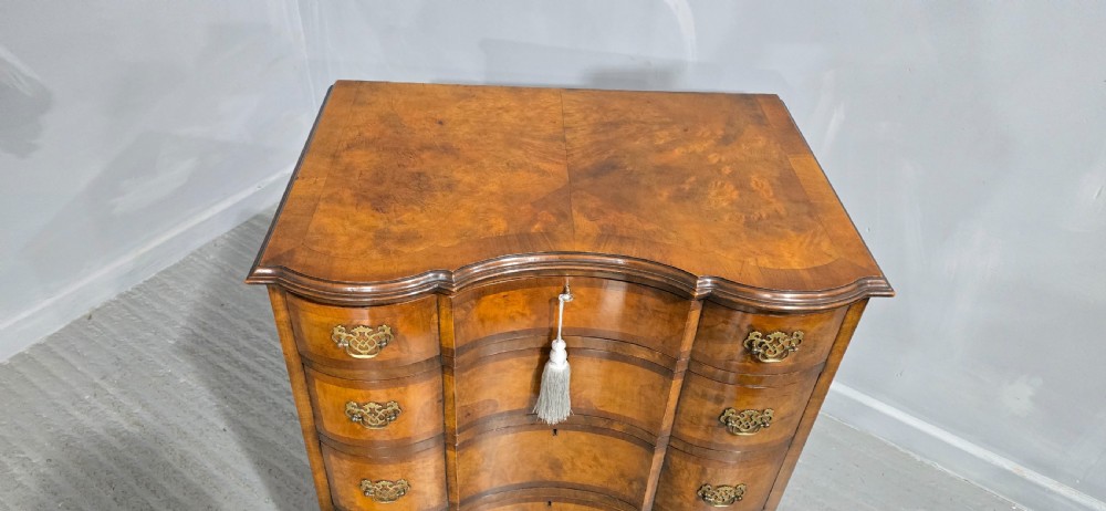 A four-drawer walnut chest of drawers featuring an inward-curving concave front, brass handles, and cabriole feet. View VI