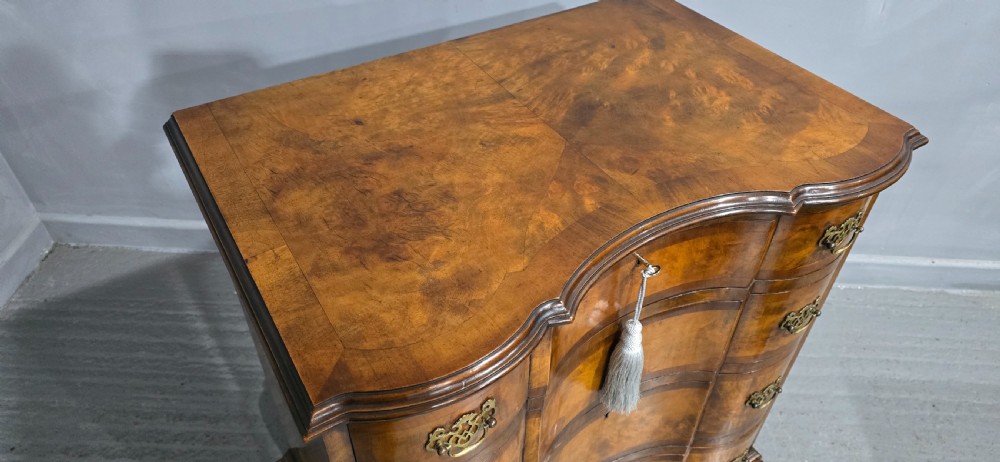 A four-drawer walnut chest of drawers featuring an inward-curving concave front, brass handles, and cabriole feet. View XV