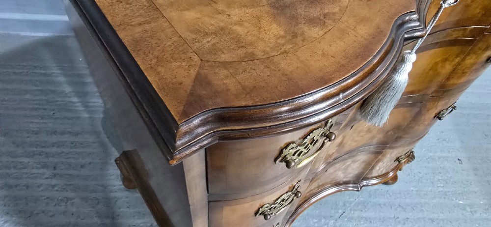A four-drawer walnut chest of drawers featuring an inward-curving concave front, brass handles, and cabriole feet. View XVI