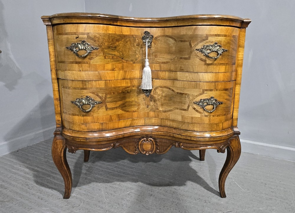 An antique walnut commode featuring two drawers with serpentine fronts, inlaid geometric banding, decorative brass handles, and carved cabriole legs. View II