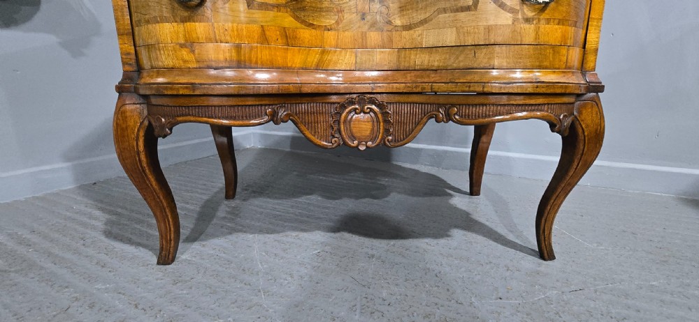 An antique walnut commode featuring two drawers with serpentine fronts, inlaid geometric banding, decorative brass handles, and carved cabriole legs. View III