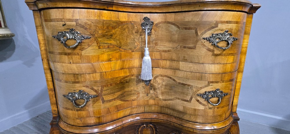 An antique walnut commode featuring two drawers with serpentine fronts, inlaid geometric banding, decorative brass handles, and carved cabriole legs. View IV
