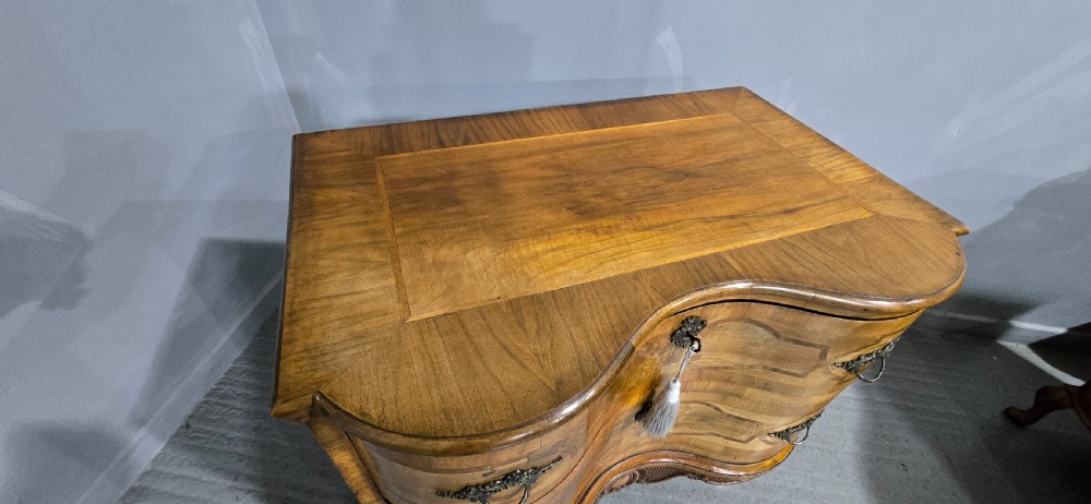 An antique walnut commode featuring two drawers with serpentine fronts, inlaid geometric banding, decorative brass handles, and carved cabriole legs. View VII