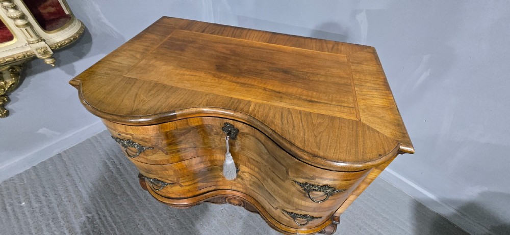 An antique walnut commode featuring two drawers with serpentine fronts, inlaid geometric banding, decorative brass handles, and carved cabriole legs. View VIII