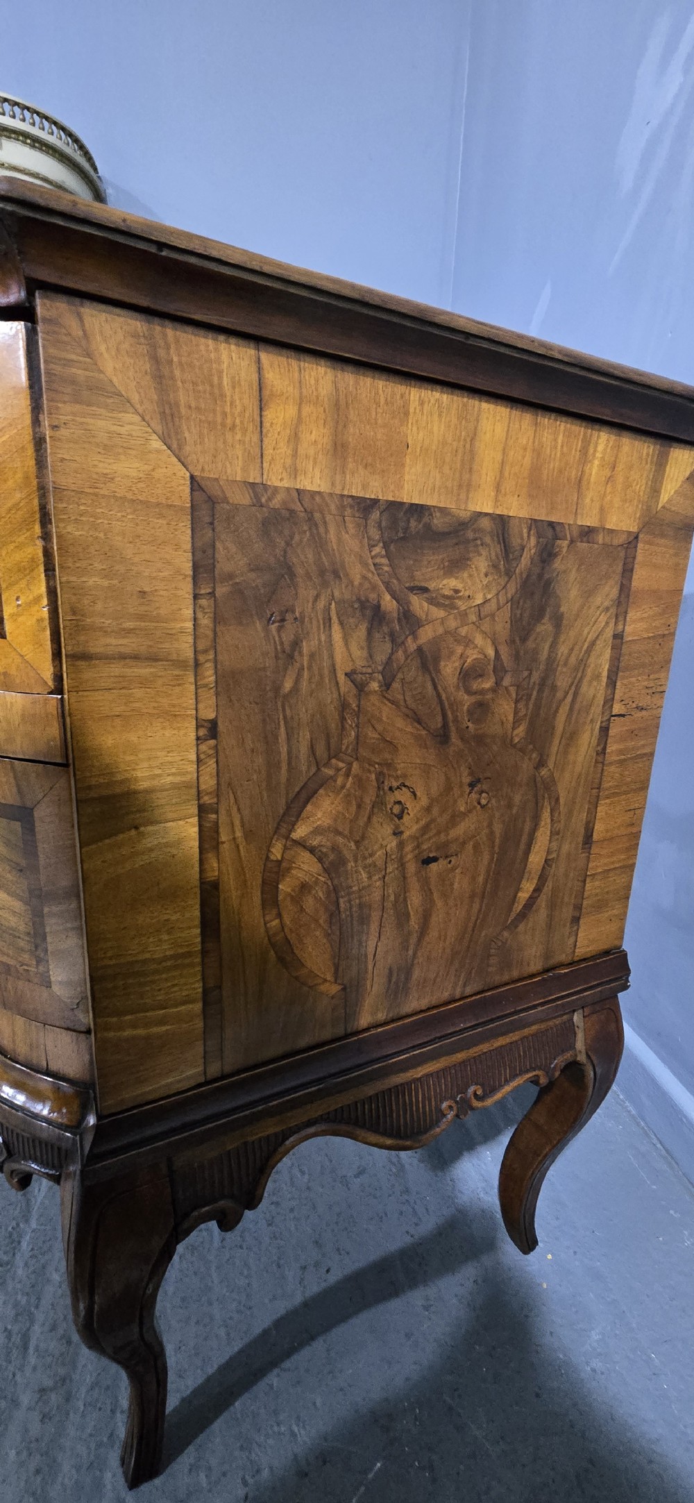 An antique walnut commode featuring two drawers with serpentine fronts, inlaid geometric banding, decorative brass handles, and carved cabriole legs. View X