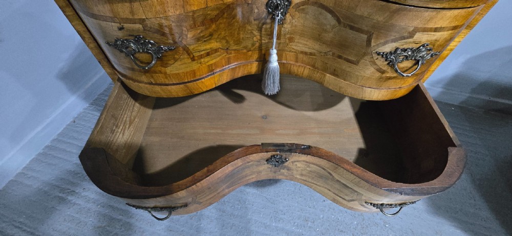 An antique walnut commode featuring two drawers with serpentine fronts, inlaid geometric banding, decorative brass handles, and carved cabriole legs. View XIII