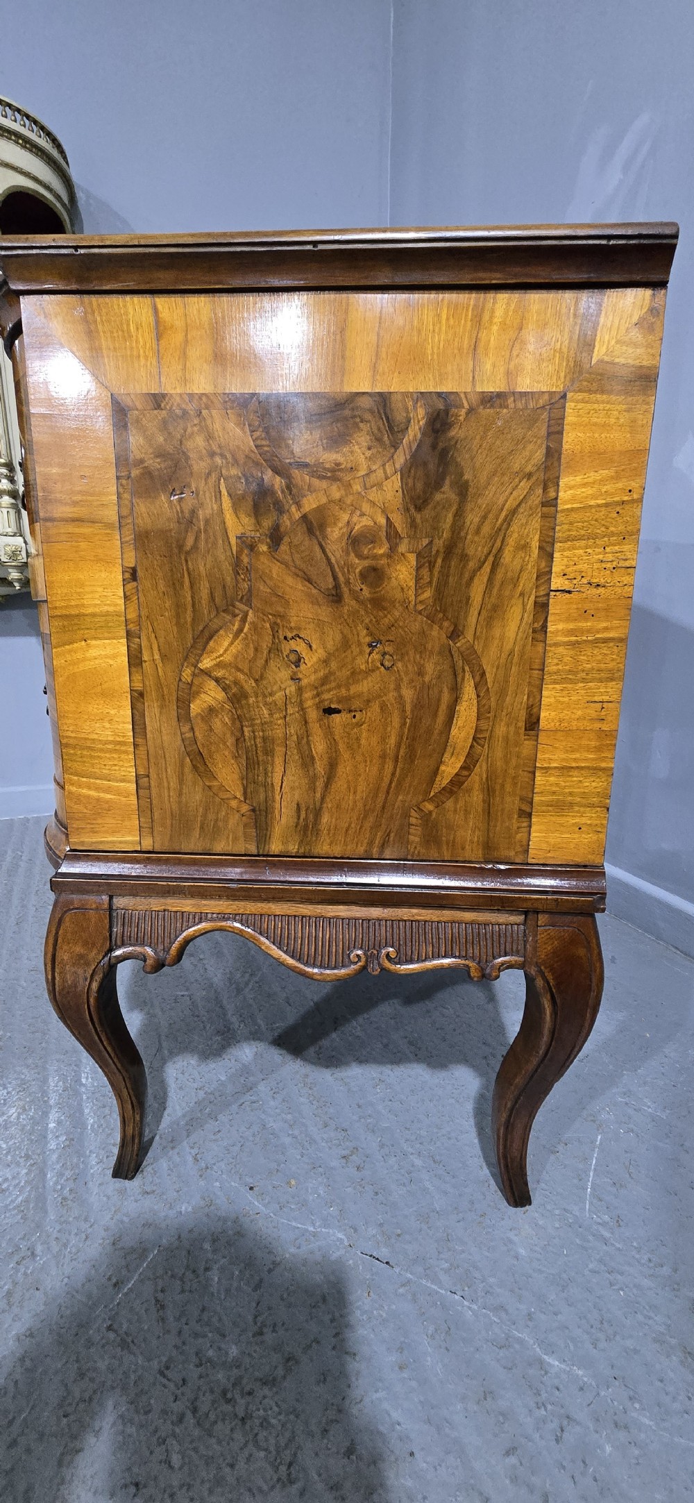 An antique walnut commode featuring two drawers with serpentine fronts, inlaid geometric banding, decorative brass handles, and carved cabriole legs. View XV