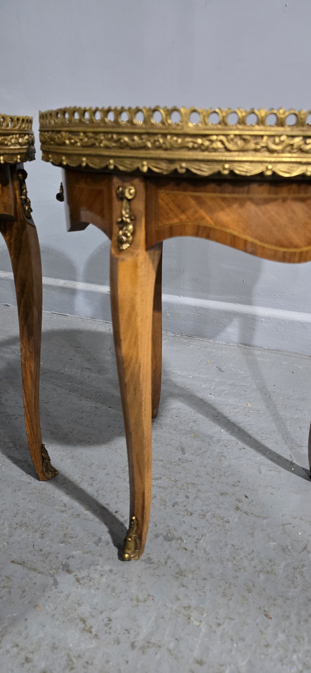 A pair of circular French kingwood side tables featuring grey marble tops, pierced brass galleries, and cabriole legs. View VII