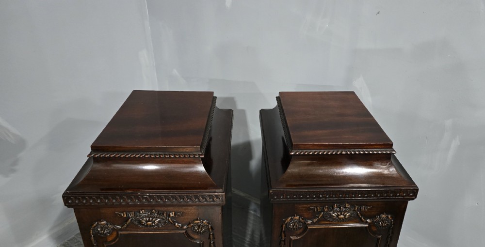 A pair of dark mahogany Regency style side cabinets featuring carved swags, floral rosettes, stepped tops, and plinth bases. View IX