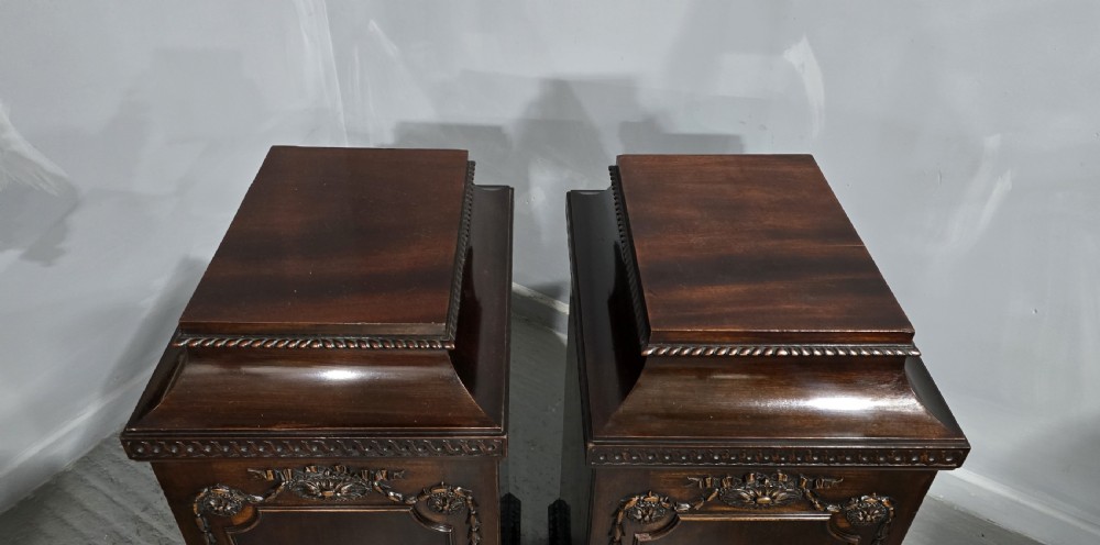 A pair of dark mahogany Regency style side cabinets featuring carved swags, floral rosettes, stepped tops, and plinth bases. View XX