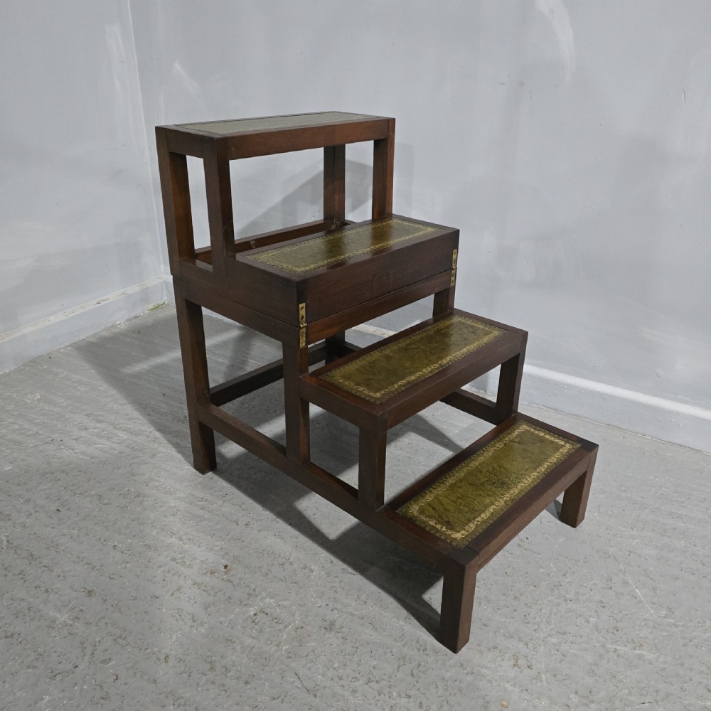 A set of dark mahogany library steps featuring four tiers inlaid with gold-tooled green leather treads.