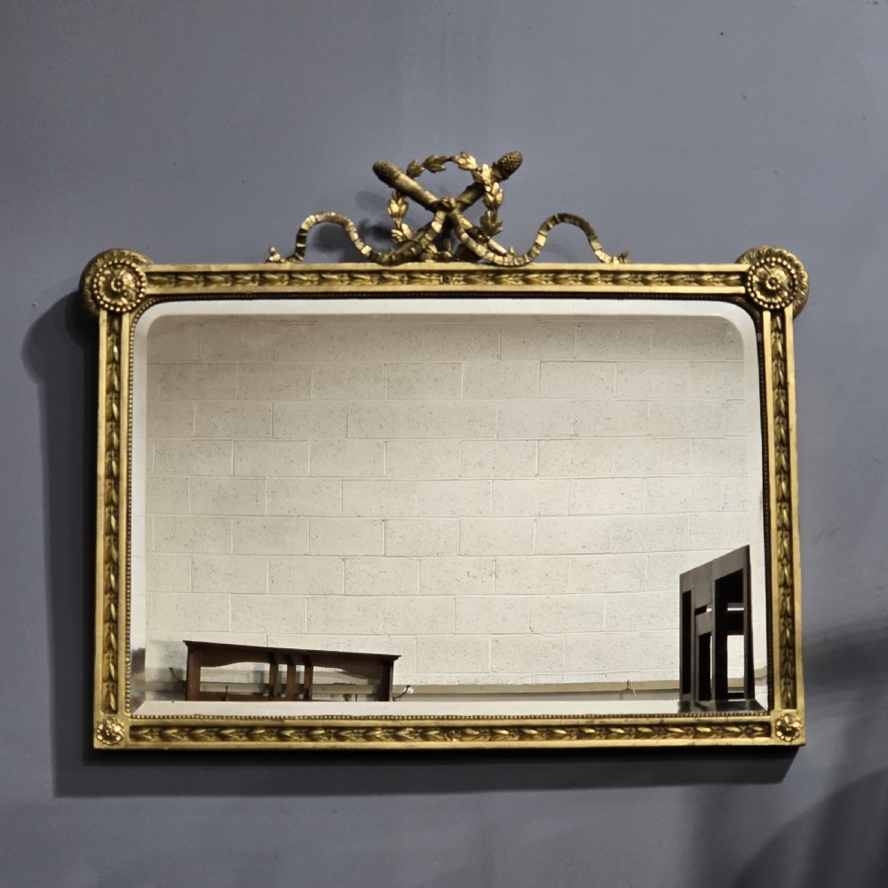 A rectangular Victorian giltwood wall mirror featuring a crested top with ribbon motifs and carved rosettes at the upper corners.