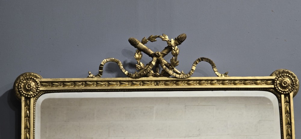 A rectangular Victorian giltwood wall mirror featuring a crested top with ribbon motifs and carved rosettes at the upper corners. View III