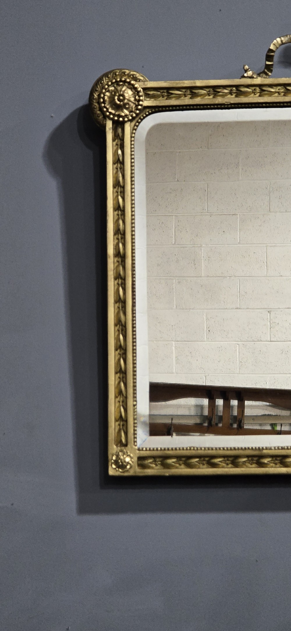 A rectangular Victorian giltwood wall mirror featuring a crested top with ribbon motifs and carved rosettes at the upper corners. View IV