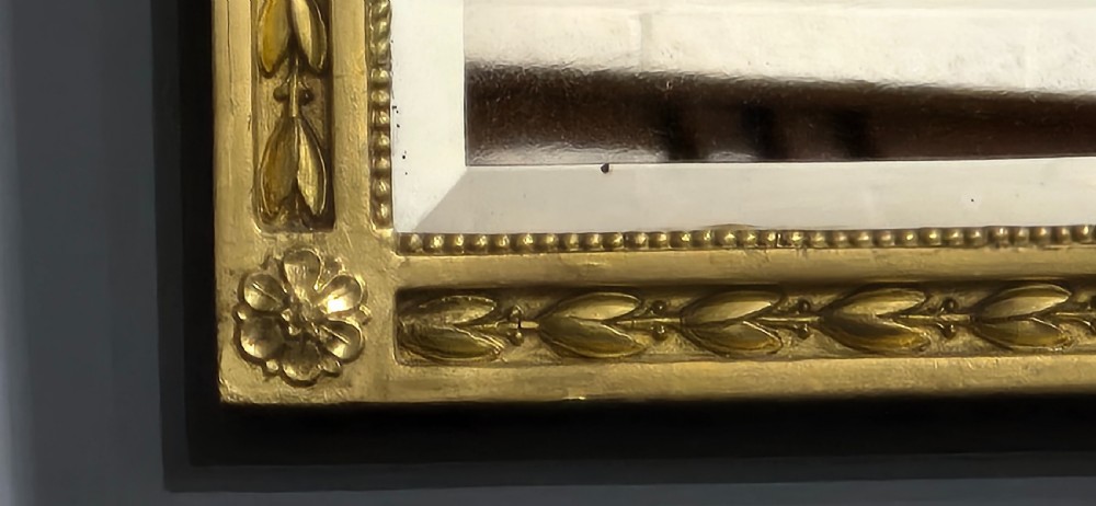 A rectangular Victorian giltwood wall mirror featuring a crested top with ribbon motifs and carved rosettes at the upper corners. View VI