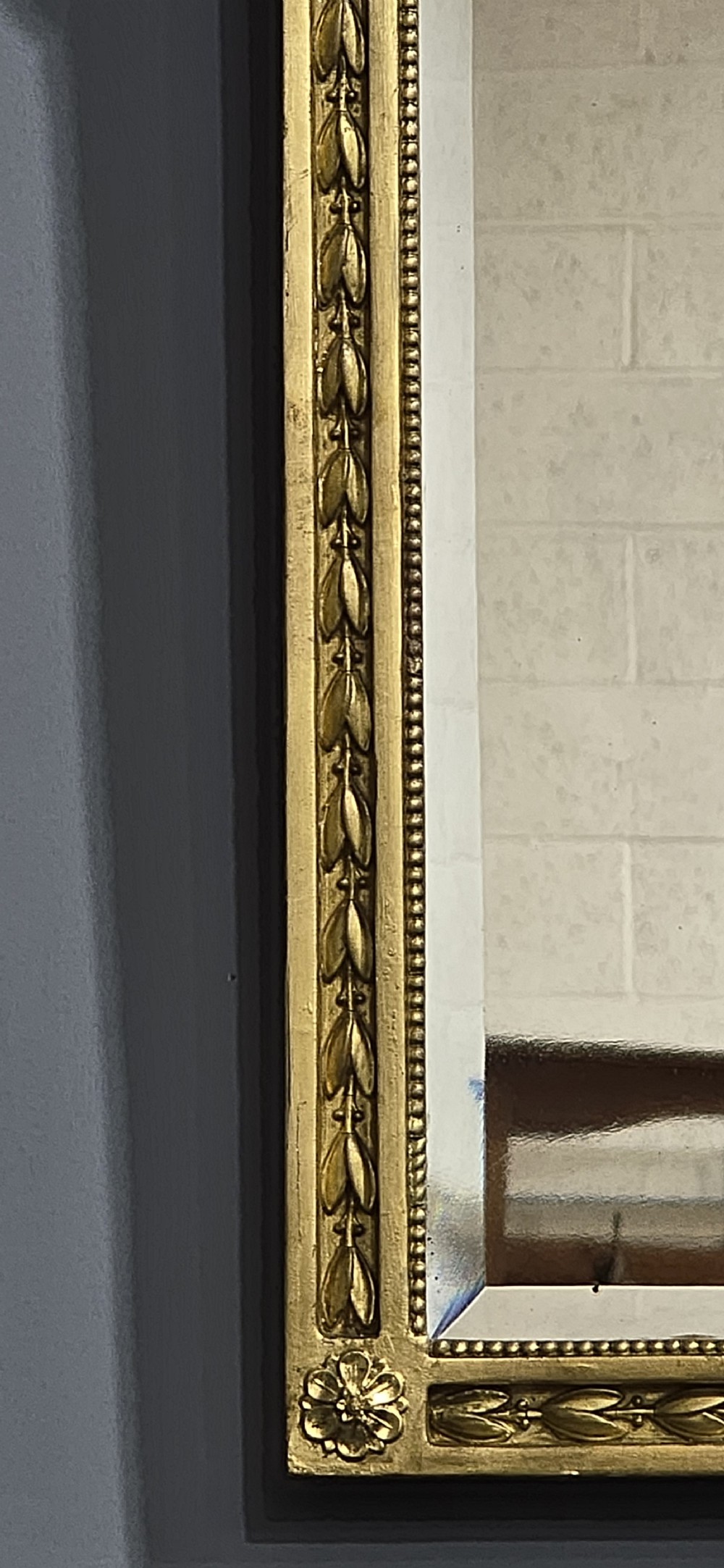 A rectangular Victorian giltwood wall mirror featuring a crested top with ribbon motifs and carved rosettes at the upper corners. View VII