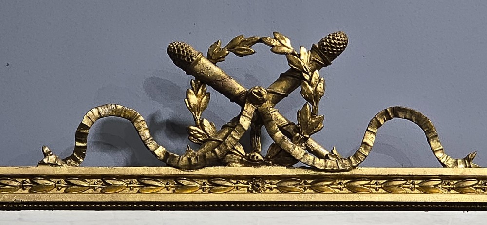 A rectangular Victorian giltwood wall mirror featuring a crested top with ribbon motifs and carved rosettes at the upper corners. View IX