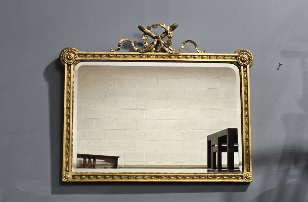 A rectangular Victorian giltwood wall mirror featuring a crested top with ribbon motifs and carved rosettes at the upper corners. View X