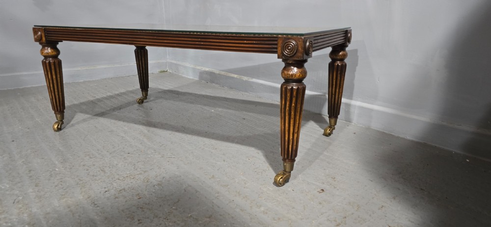 A low rectangular mahogany coffee table featuring a glass-covered woven cane top, reeded frieze, carved corner rosettes, and tapered reeded legs terminating in brass castors. View IV