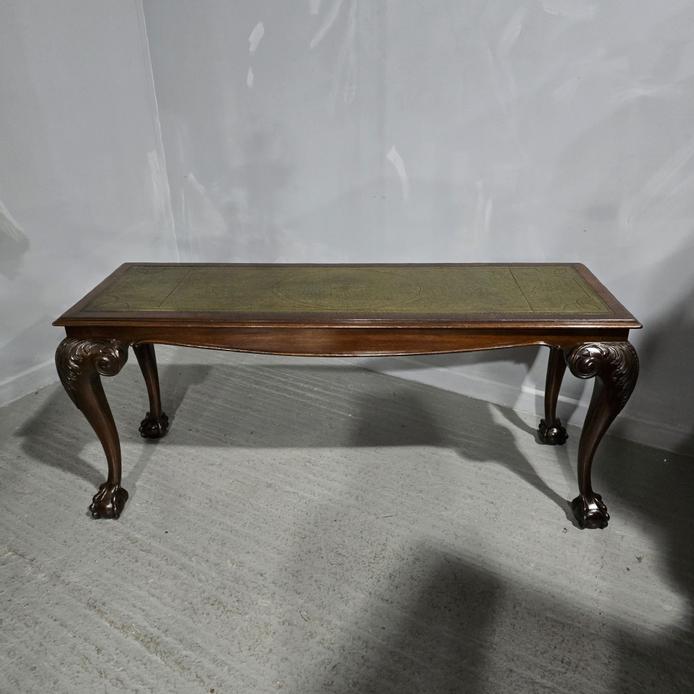 A mahogany console table featuring a green gold-tooled leather inset top and carved cabriole legs ending in ball-and-claw feet.