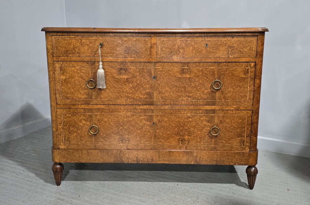 A French amboyna chest of drawers featuring two short drawers over two long drawers, brass ring handles, and turned reeded feet. View II